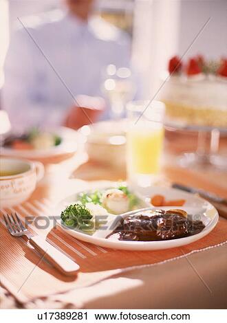 Stock Image - Meal on table with man in background. Fotosearch
