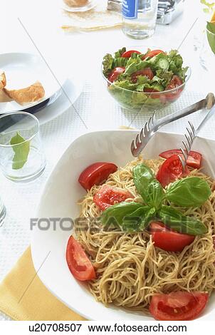 Stock Photo - Pasta dish with tomatoes and salad. Fotosearch