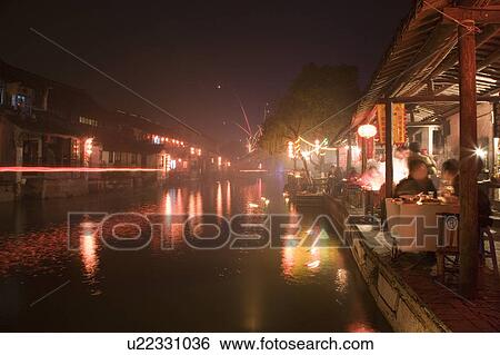 Stock Photograph - People eating at restaurant by river, Xi Tang, China. Fotosearch