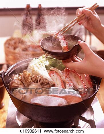 Stock Image - Person dipping crab leg in sauce. Fotosearch