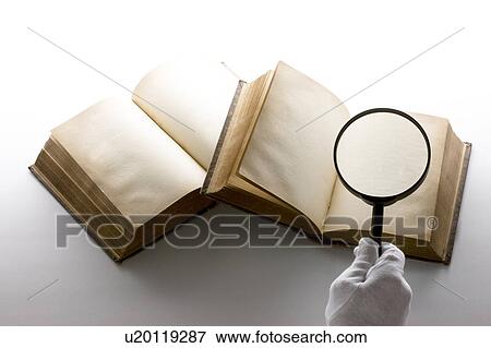 Stock Photo - Person holding magnifying glass over book. Fotosearch
