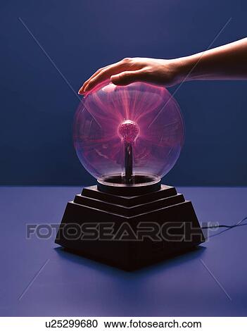 Stock Image - Person placing hand on plasma lamp. Fotosearch