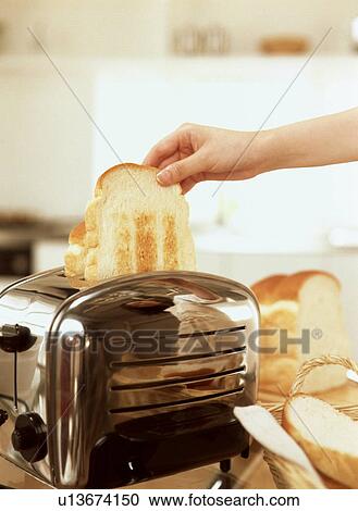 Stock Image - Person taking bread out of toaster. Fotosearch