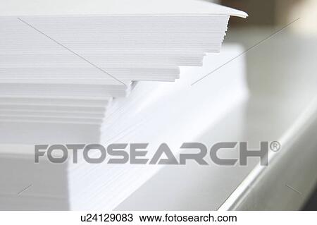 Stock Image - Piled papers on desk, close up. Fotosearch