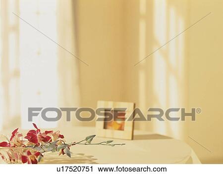 Stock Image - Pink flowers and picture frame on table. Fotosearch