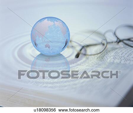 Stock Photograph - Planet earth on book next to glasses. Fotosearch
