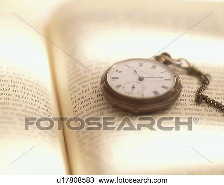 Stock Image - Pocket watch on book, close up. Fotosearch