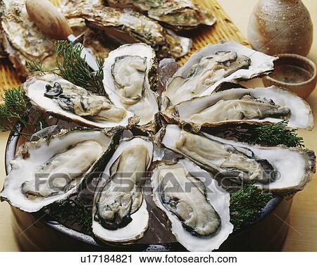 Stock Image - Raw oyster with sake. Fotosearch