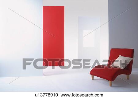 Stock Image - Red armchair in room with red and white walls. Fotosearch