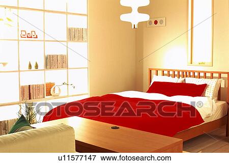 Stock Photo - Red bed in bedroom next to bookshelf. Fotosearch