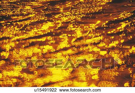 Stock Image - Ripples on water in gold sunlight. Fotosearch