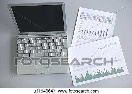 Stock Photo - Rising graphs on papers and laptop, white background. Fotosearch
