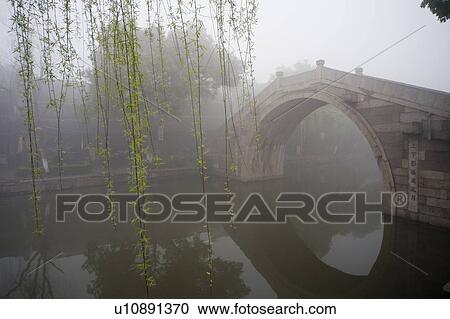 Stock Image - Riverside in the morning fog, Xi Tang, China. Fotosearch