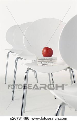 Stock Photograph - Row of chairs with an apple and books. Fotosearch