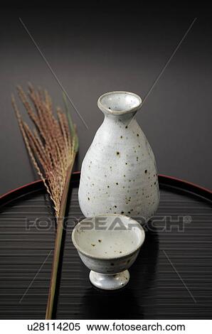 Stock Photography - Sake cup and bottle on tray, black background. Fotosearch