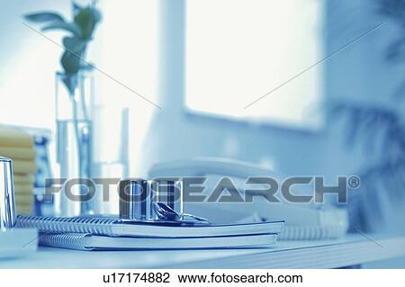 Stock Image - Silver coffee cup on spiral notebooks next to telephone. Fotosearch