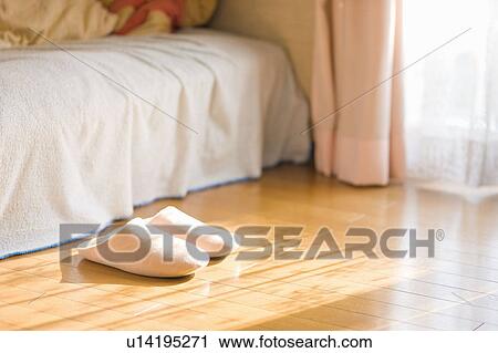 Stock Image - Slippers on floor next to bed and window. Fotosearch