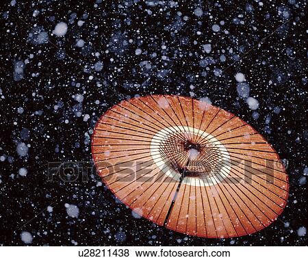 Stock Photo - Snow falling over a paper umbrella.. Fotosearch