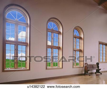 Stock Image - Spacious room with arched windows and pew. Fotosearch