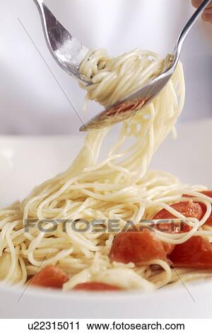 Stock Image - Spaghetti with tomato in fork and spoon. Fotosearch