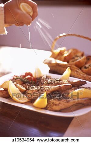 Picture - Squeezing lemon onto chicken. Fotosearch