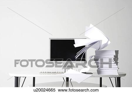 Stock Photography - Stack of paper in front of computer monitor. Fotosearch