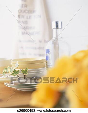 Stock Photo - Stacked plates and a bottle of vodka on a table. Fotosearch
