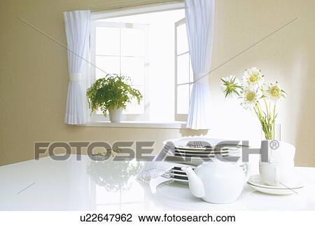 Stock Image - Stacked plates and teapot on table. Fotosearch