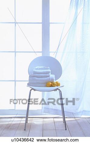 Stock Image - Stacked towels and lemons on white chair. Fotosearch
