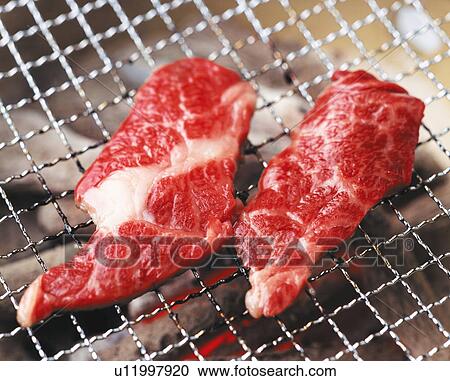 Stock Image - Steaks on a charcoal brazier. Fotosearch