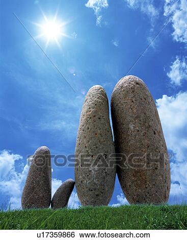Stock Photograph - Stones on grass under a blue sky. Fotosearch