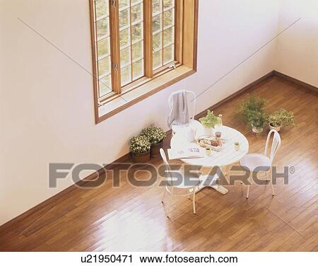Stock Image - Table and chairs by window with pot plants. Fotosearch