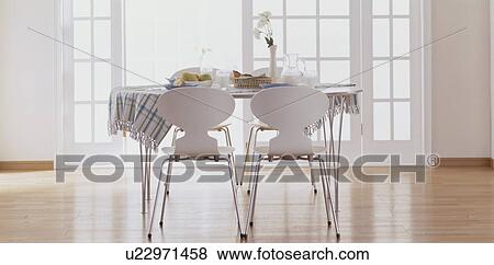 Table and chairs with food in spacious room View Large Photo Image Stock Photo - Table and chairs with food in spacious room. Fotosearch