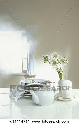 Stock Image - Tableware and a teapot stacked in the sunlight. Fotosearch