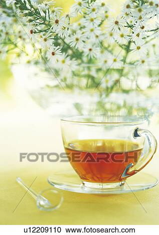 Stock Image - Tea in a glass mug and a bunch of daisies. Fotosearch