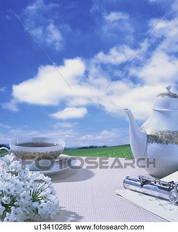 Stock Photography - Tea picnic with flowers and a flute. Fotosearch