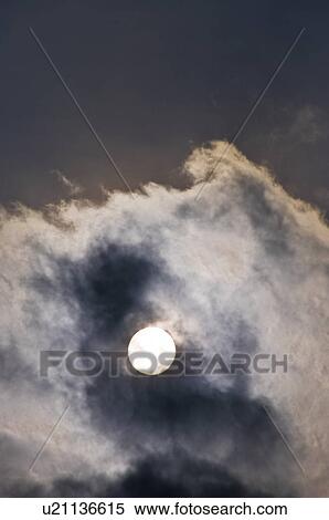 Stock Photography - The Sun Appearing Behind Dark Clouds. Fotosearch