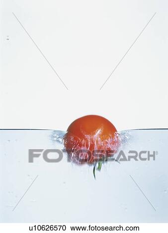 Stock Image - Tomato falling into water. Fotosearch