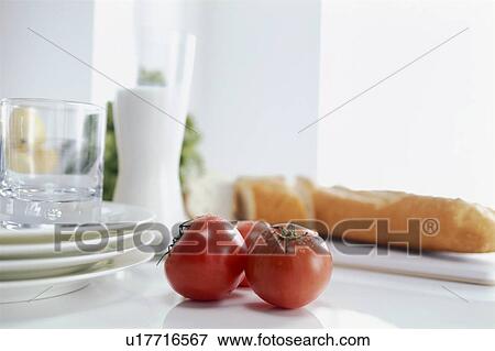 Stock Photo - Tomatoes and baguette with plates and glass. Fotosearch