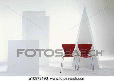 Stock Image - Two red chairs in room with white shapes. Fotosearch