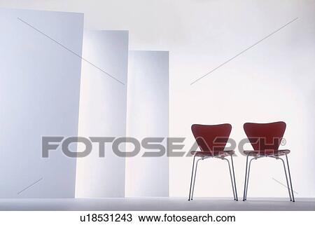 Stock Image - Two red chairs in room with white walls. Fotosearch