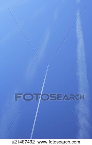 Stock Image - Vapor trails in the sky, blue background. Fotosearch