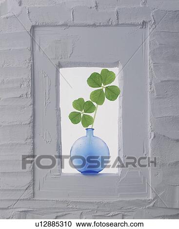 Stock Image - Vase of four leaf clovers in window of a wall. Fotosearch