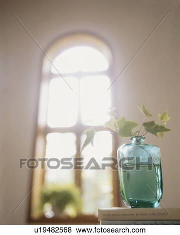 Stock Photo - Vase on books with sunlight coming through window. Fotosearch