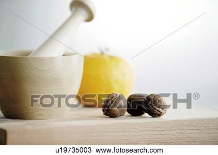 Stock Image - Walnuts by wooden mortar and pestle, white background. Fotosearch