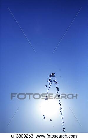 Stock Image - Water drops against blue sky, blue background, copy space. Fotosearch