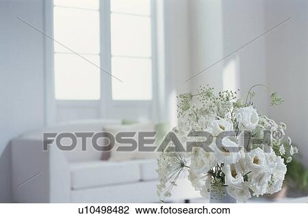 Stock Image - White flowers with sofa in background. Fotosearch