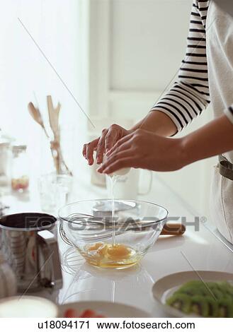 Stock Image - Woman cracking egg into glass bowl. Fotosearch