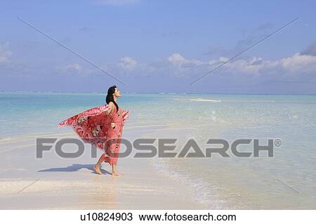 Stock Image - Woman enjoying the breeze at the beach, Maldive Islands. Fotosearch