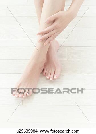 Picture - Woman giving herself a leg massage. Fotosearch